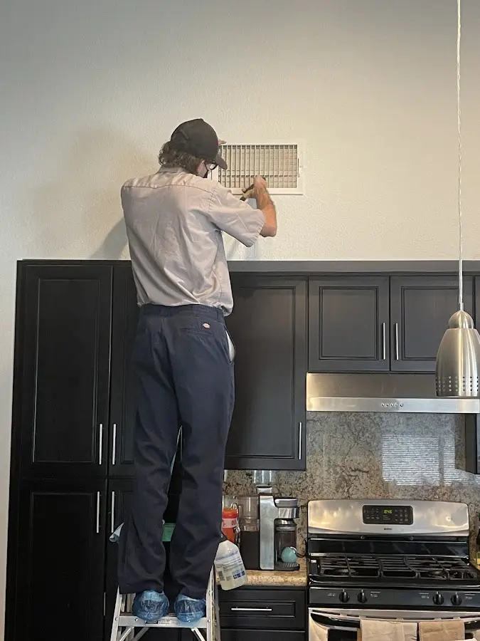 Technician inspecting an air vent during HVAC service in Yucaipa